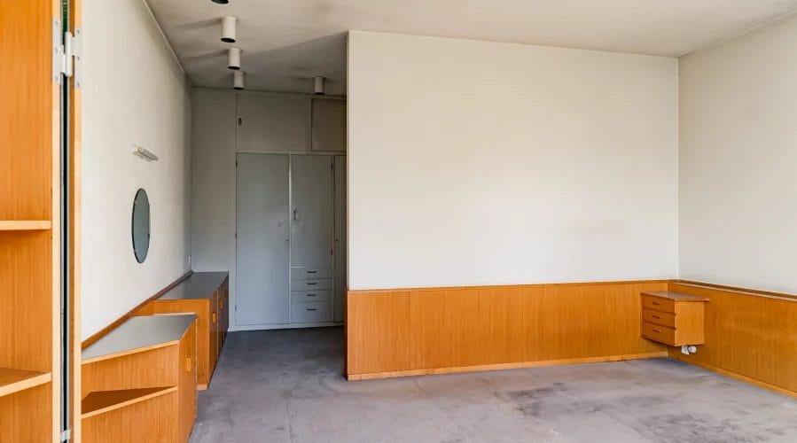 Een lege kamer met houten wanden en planken.