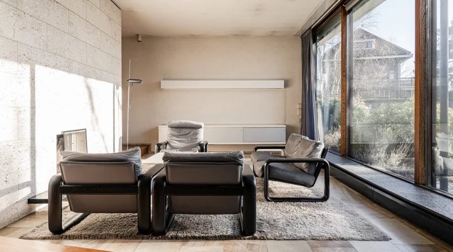 Een woonkamer met een open haard en grote raampartijen.