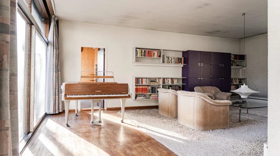 Een woonkamer met een piano en boekenkasten.