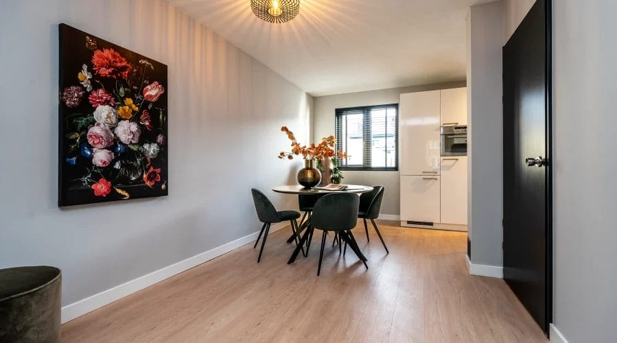 Een eetkamer met houten vloeren en een schilderij aan de muur. meubels huren, meubelverhuur luxe pakket