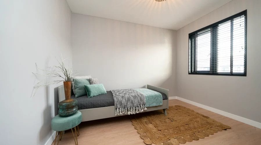 Een kleine slaapkamer met een bed en een raam. meubels huren, meubelverhuur luxe pakket