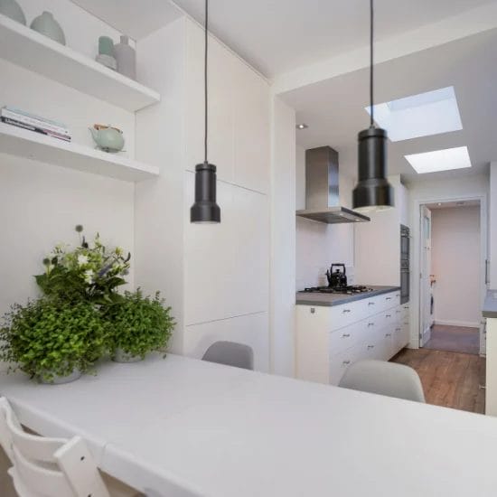 Een witte keuken met een tafel en stoelen. verkoopstyling schiedam, neutrale inrichting, woningfotografie