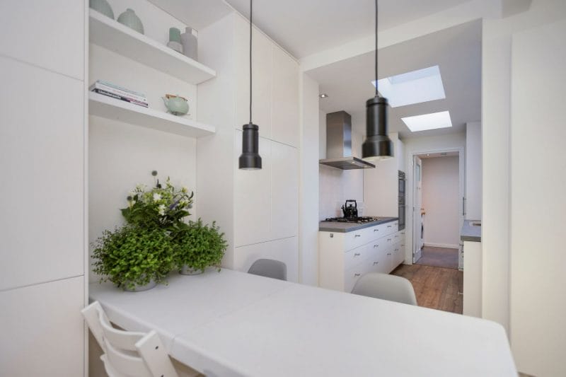 Een witte keuken met een tafel en stoelen. verkoopstyling schiedam, neutrale inrichting, woningfotografie