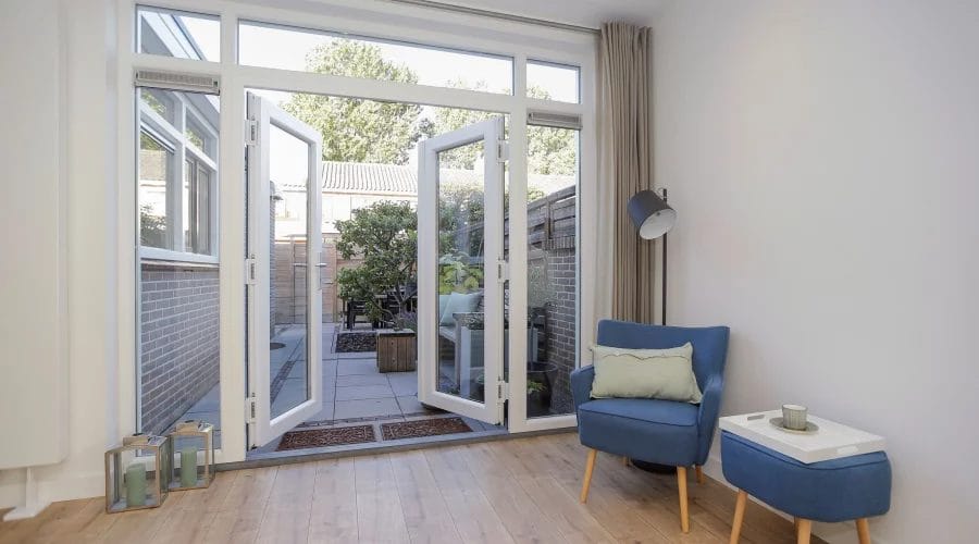 Een woonkamer met een deur naar een patio. verkoopstyling schiedam, neutrale inrichting, woningfotografie