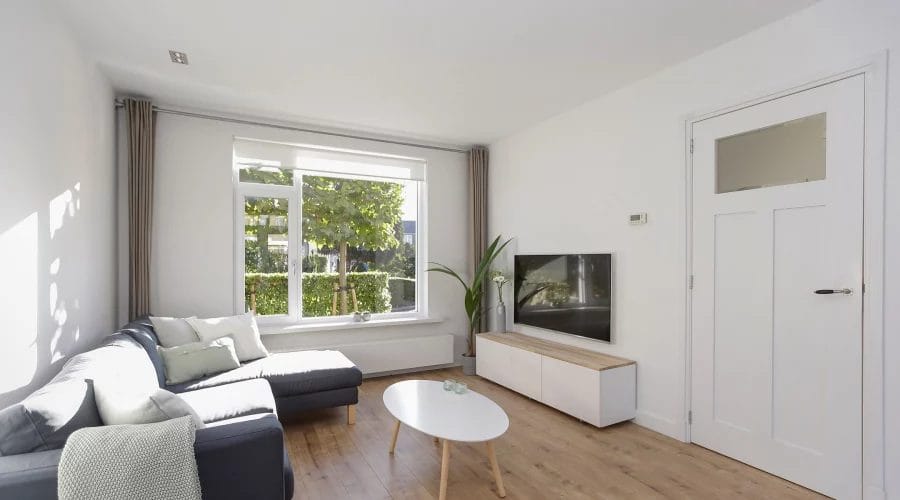 Een woonkamer met een bank en een tv. verkoopstyling schiedam, neutrale inrichting, woningfotografie