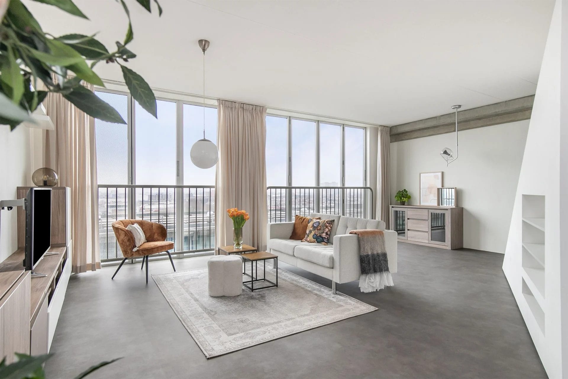 Een woonkamer met grote ramen en uitzicht op de stad.