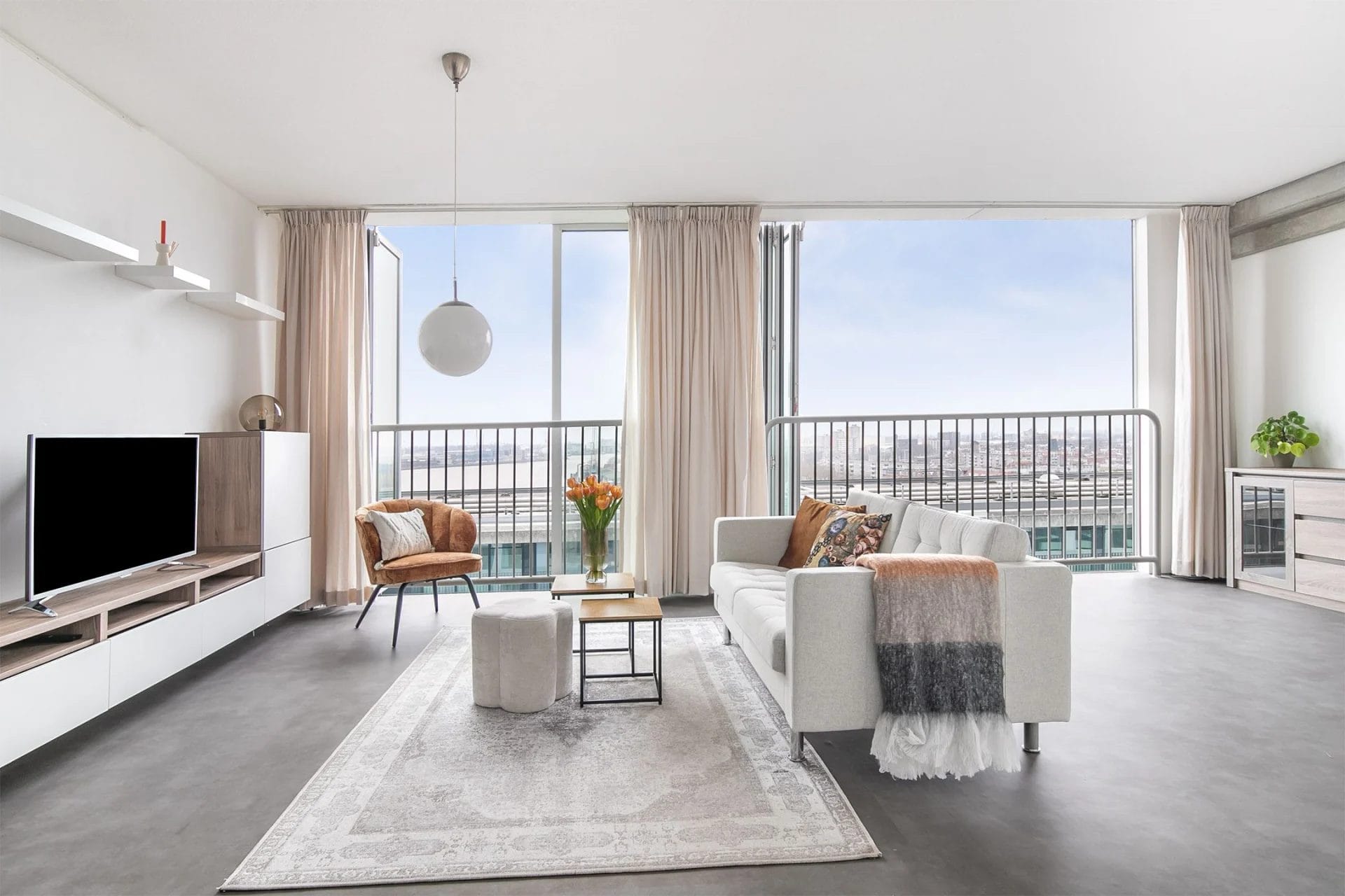 Een woonkamer met een groot raam met uitzicht op de stad.