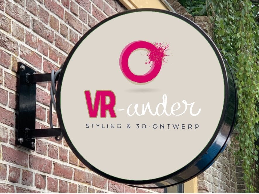 Rond winkelbord op een bakstenen muur met de tekst "VR-ander Styling & 3D-Ontwerp" met roze verfspatten en een cirkelvormig logo boven de tekst.